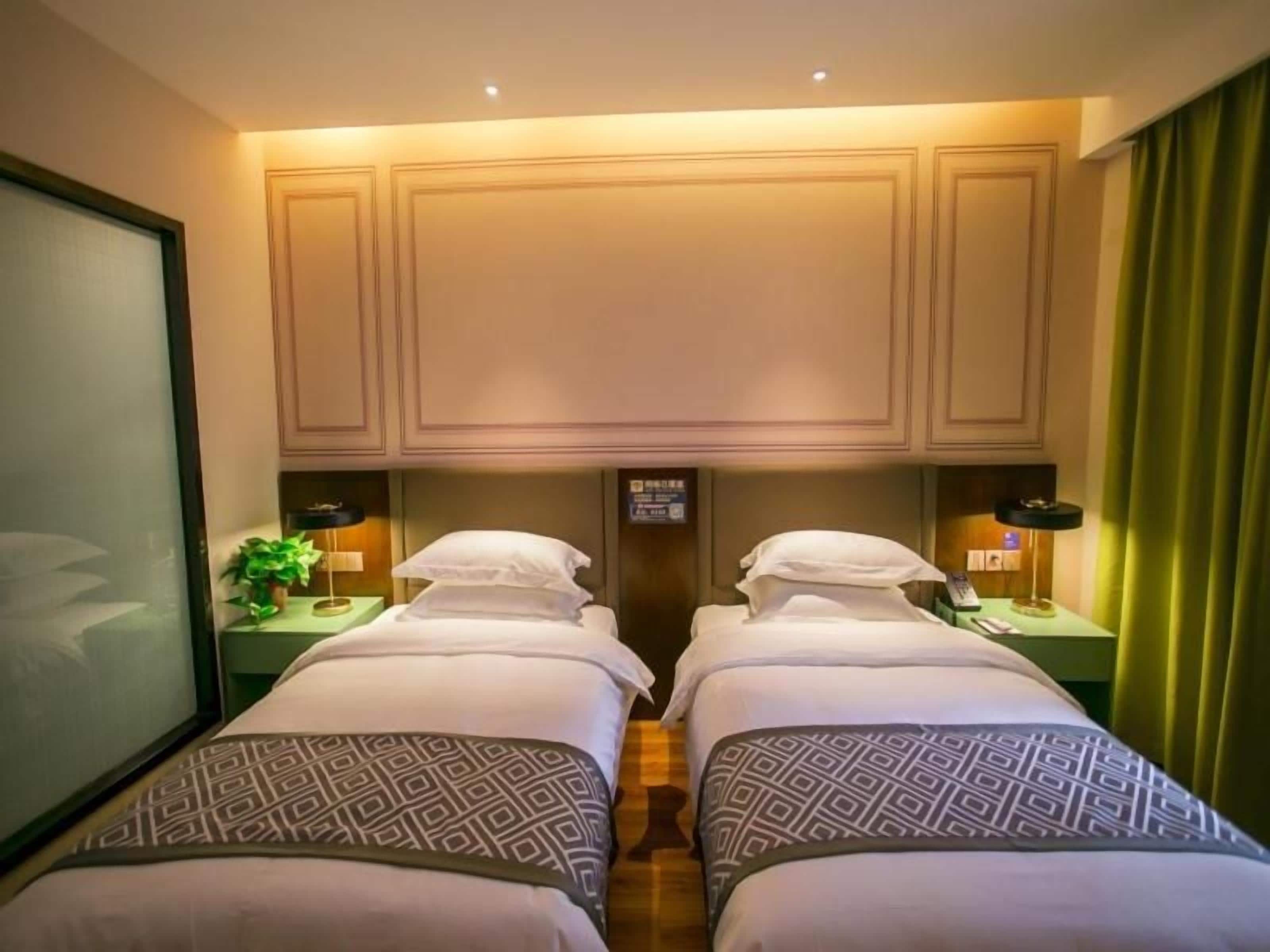 Ein Hotelzimmer mit zwei Betten, einem grünen Vorhang und einem kleinen Tisch mit einer Lampe.