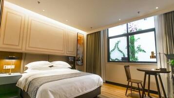 Una habitación de hotel con una cama, un escritorio, una silla y un ventanal con cortinas.
