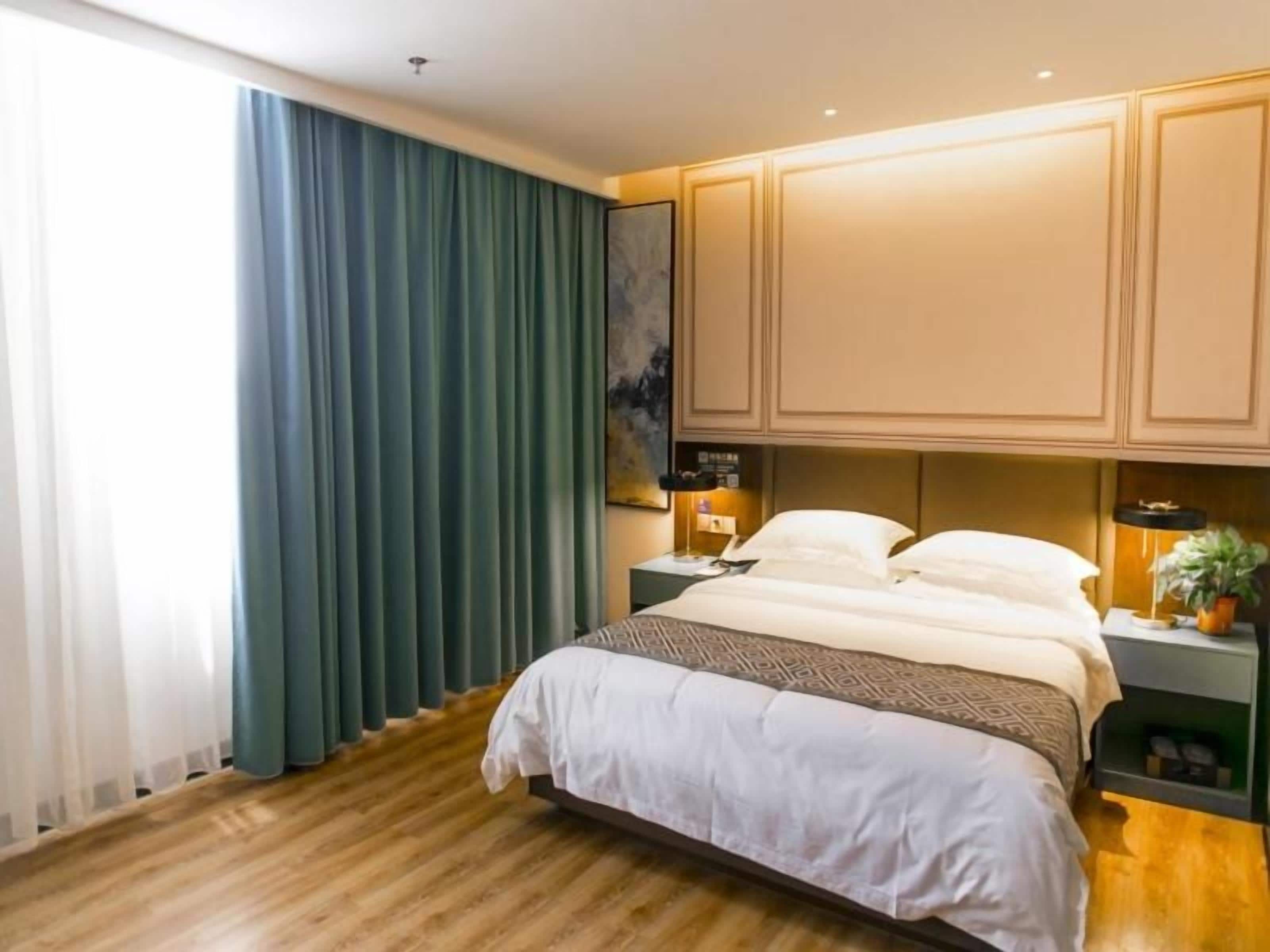 Et hotelværelse med en stor seng, et natbord, en lampe og et billede på væggen.
