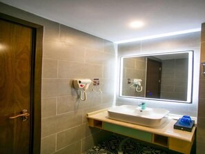 A bathroom with a sink, mirror, hairdryer, and towel rack. - Gem Bozhou Qiaocheng District Jian 'an Road Railway Station Hotel (Bozhou)