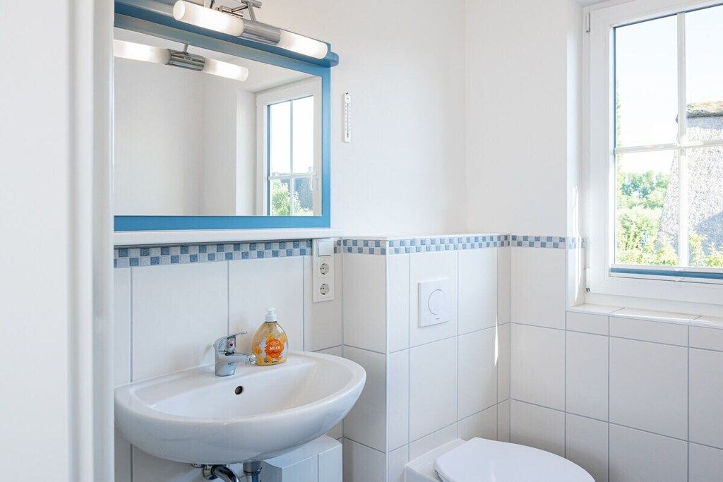 A bathroom with a white sink, a mirror, and a toilet.