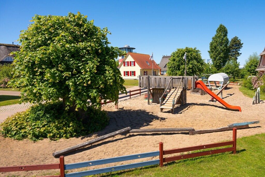 Ein Spielplatz mit Rutsche, Klettergerüst und Sandkasten.