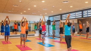 Un grupo de personas en un gimnasio, con colchonetas de ejercicio y un espejo grande.