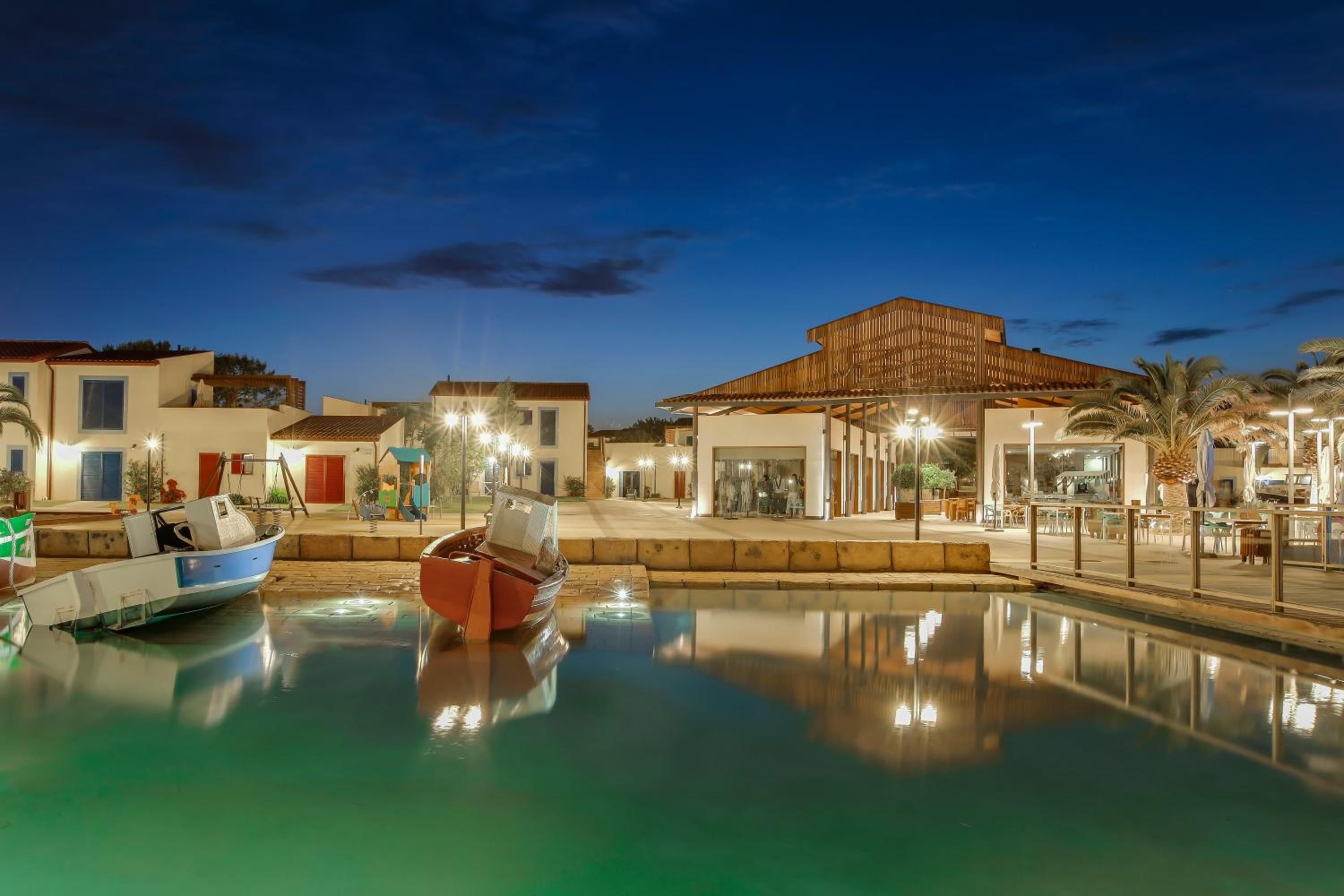 Una proprietà sul lungomare con piscina, imbarcazioni e edifici con posti a sedere all'aperto.