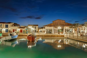 Una propiedad frente al mar con piscina, barcos y edificios con terrazas al aire libre.