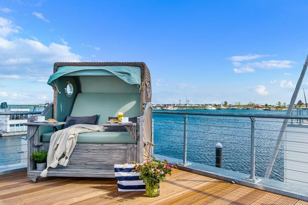 A deck with a cushioned seating area, a small table, and a potted plant.