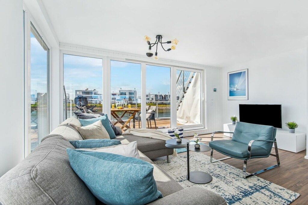 A modern living room with a large sofa, a television, and a view of the city through large windows.