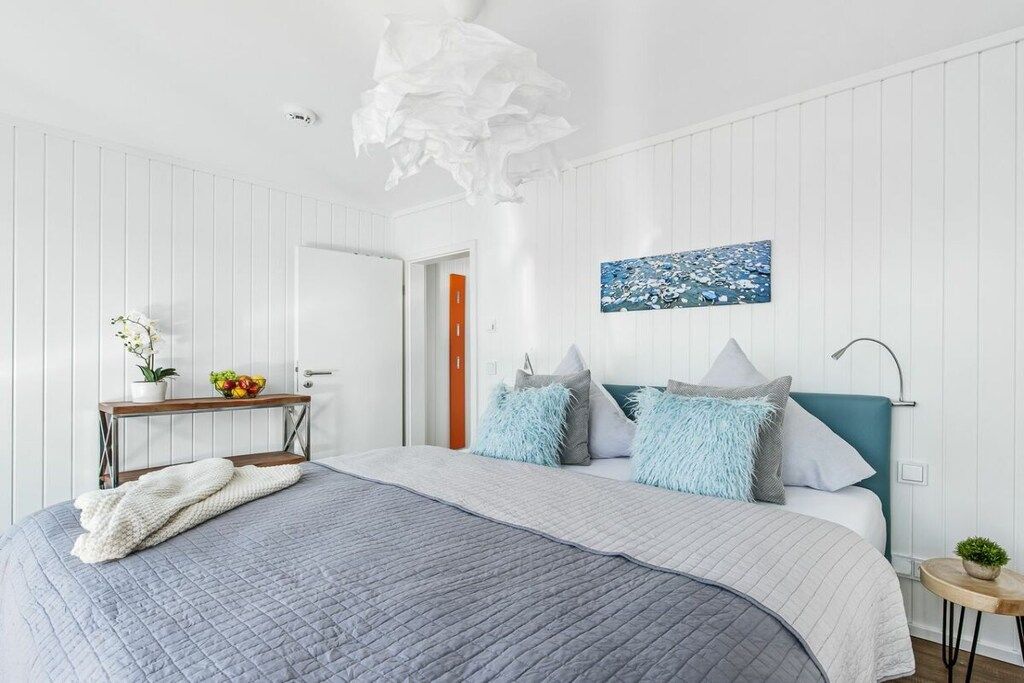 Een moderne slaapkamer met een bed, nachtkastje en een schilderij aan de muur.