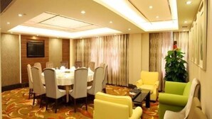 A conference room with a round table and chairs, a television on the wall, and a plant. - Shenzhen Futian Huaqiang South Feiyuan Hotel (Shenzhen)