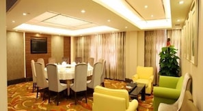 A conference room with a round table and chairs, a television on the wall, and a plant. - Shenzhen Futian Huaqiang South Feiyuan Hotel (Shenzhen)