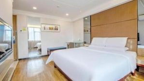 A hotel room with a large bed, a bedside table, a TV, and a wooden headboard. - Shenzhen Futian Huaqiang South Feiyuan Hotel (Shenzhen)