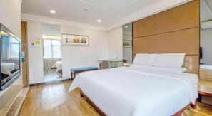 A hotel room with a large bed, a bedside table, a TV, and a wooden headboard. - Shenzhen Futian Huaqiang South Feiyuan Hotel (Shenzhen)