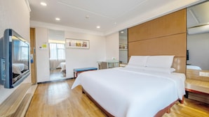 A hotel room with a large bed, a television, a desk, and a mirror. - Shenzhen Futian Huaqiang South Feiyuan Hotel (Shenzhen)