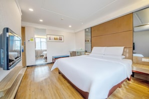 A hotel room with a large bed, a television, a desk, and a mirror. - Shenzhen Futian Huaqiang South Feiyuan Hotel (Shenzhen)