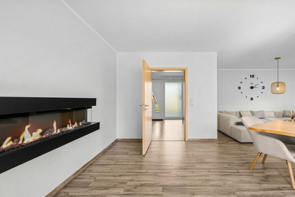 A modern living room with a fireplace, a dining area, and a sofa.