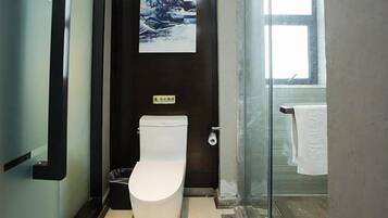 A modern bathroom with a toilet, a glass shower enclosure, and a visible window.