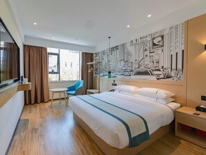 A hotel room with a large bed, a desk, a chair, a window with curtains, and a wall mural. - City Comfort Inn (Shantou)