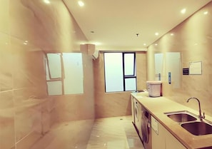 A modern kitchen with a built-in washing machine, a sink, and a window. - City Comfort Inn (Shantou)