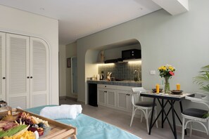 A modern kitchen with a dining area, a bed with a blue bedspread, and a breakfast tray with fruits and cheese. - Vintage stay bait assel by spacey 105 (cairo)