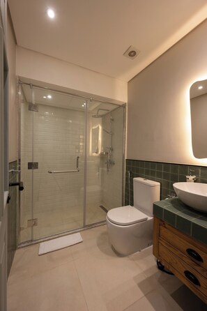 A modern bathroom with a glass-enclosed shower, a white toilet, and a wooden vanity with a sink. - Vintage stay bait assel by spacey 105 (cairo)