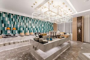 Un hall d’hôtel moderne avec un comptoir de réception en marbre, un mur orné de motifs et un luminaire au plafond aux formes géométriques.