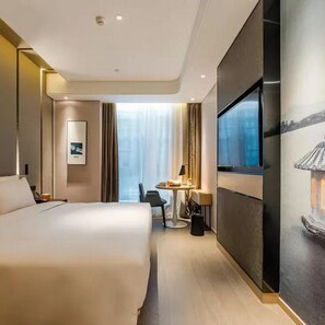 Une chambre d’hôtel avec un grand lit, un bureau, une chaise et un téléviseur fixé au mur.