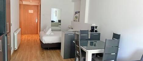 Una habitación de hotel moderna con una cama, un escritorio con una silla, un sofá y suelo de madera.