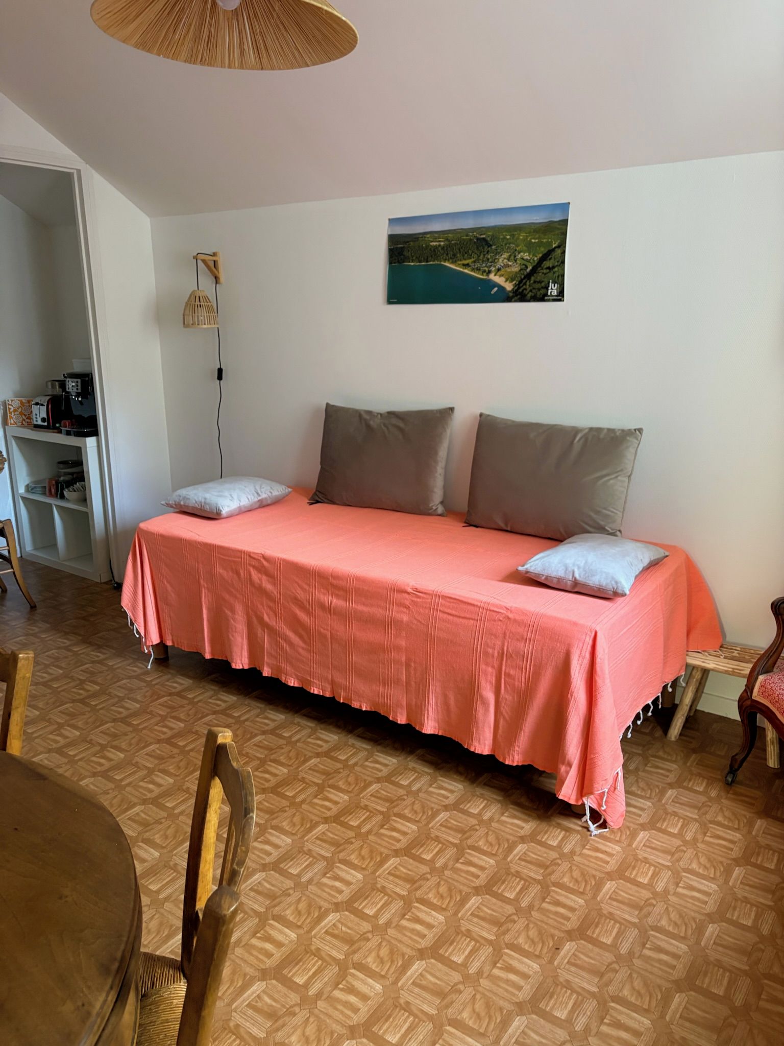 A room with a bed, a dining table, chairs, a hanging light fixture, and a wall-mounted picture.