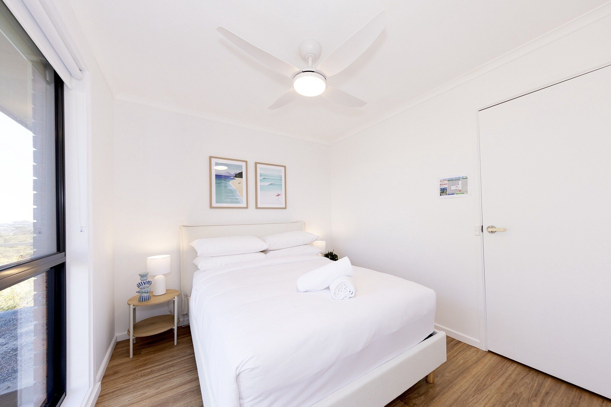 Ein Hotelzimmer mit Bett, Nachttisch, Deckenventilator und Tür.
