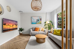 A modern living room with a sofa set, a coffee table, a painting, and a potted plant. - Designer 2BR Terrace | BBQ Garden near Moore Park (Redfern)