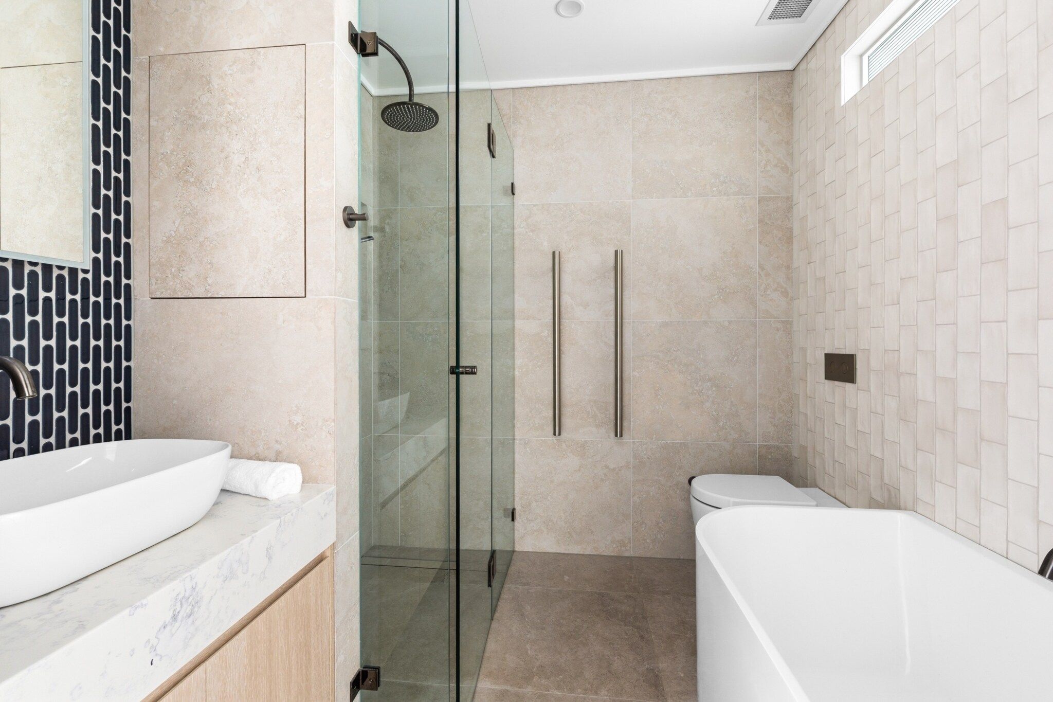 Un bagno moderno con cabina doccia in vetro, vasca da bagno bianca e servizi igienici.