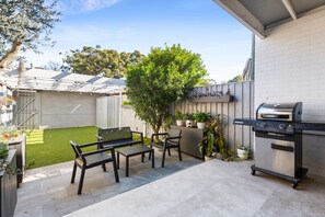 Eine Außenpatio mit Grill, Sitzbereich und kleinem Rasen.