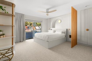 Ein modernes Schlafzimmer mit Bett, Deckenventilator und Blick ins Freie.