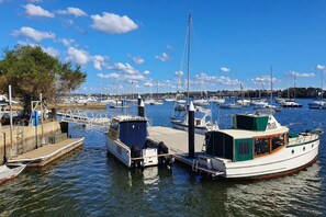 A marina with multiple boats docked, a wooden pier, and a clear blue sky. - Botany Retreat 2-Bed Granny Flat With Pool (Botany)