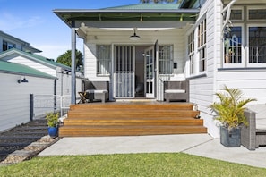 A two-story house with a porch, wooden steps, and outdoor seating. - Botany Retreat 2-Bed Granny Flat With Pool (Botany)