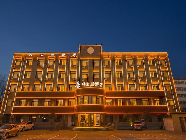 A hotel with a prominent entrance, multiple floors, and a parking lot. - Magnotel (Jinzhong)