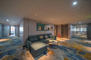 Un hall de hotel con un sofá, una mesa de centro y obras de arte en la pared.