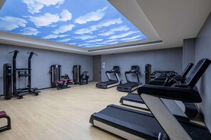 Un gimnasio con cintas de correr, elípticas y equipos de pesas.