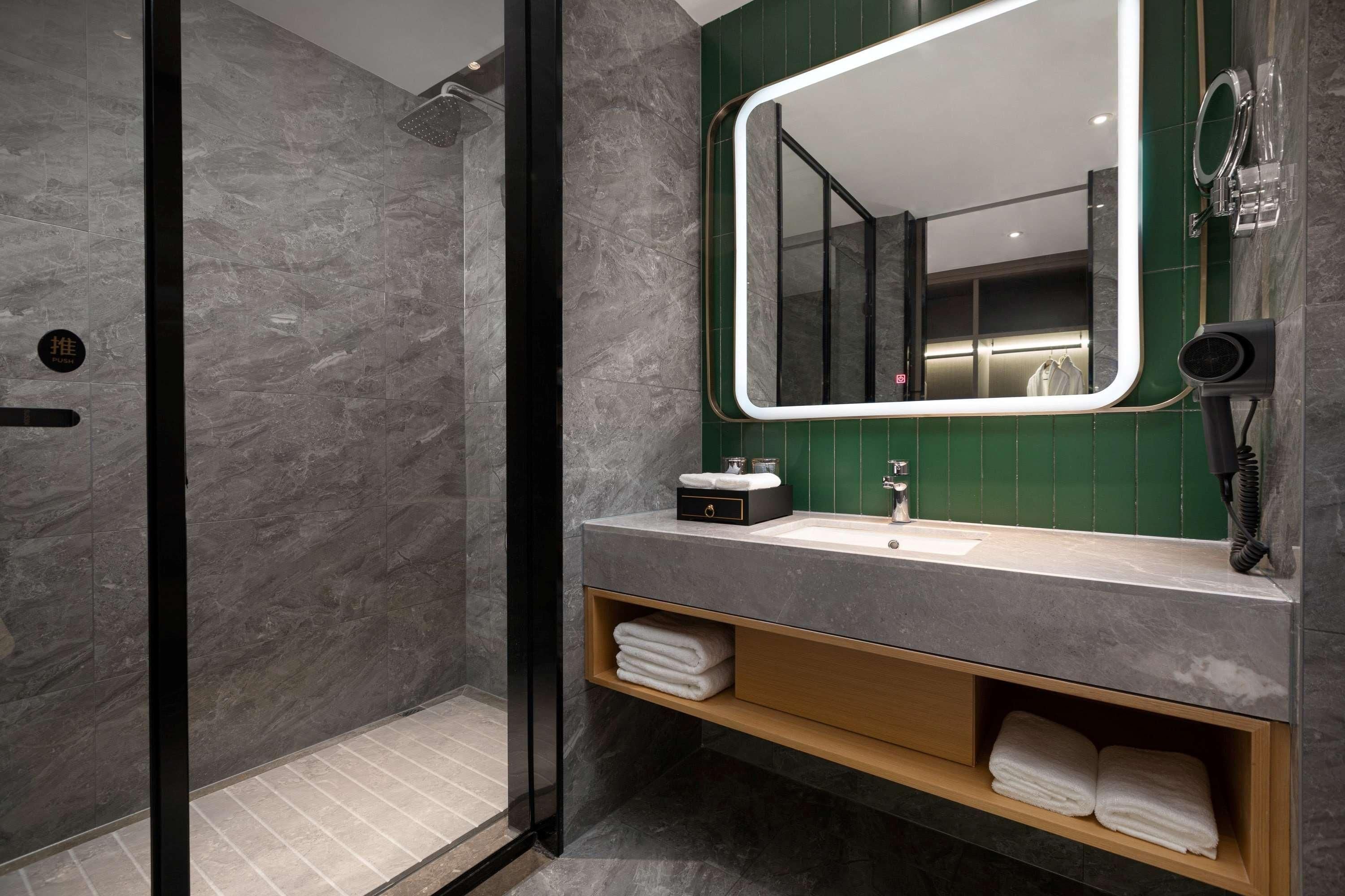 A modern bathroom with a glass-enclosed shower, a vanity with a mirror, and a towel rack.