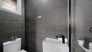 Un baño moderno con inodoro, lavamanos y zona de ducha.