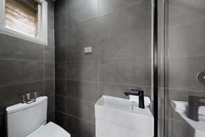 A modern bathroom with a toilet, a sink, and a shower area. - Spacious 4-Bed House with Garden in Glenroy (Glenroy)