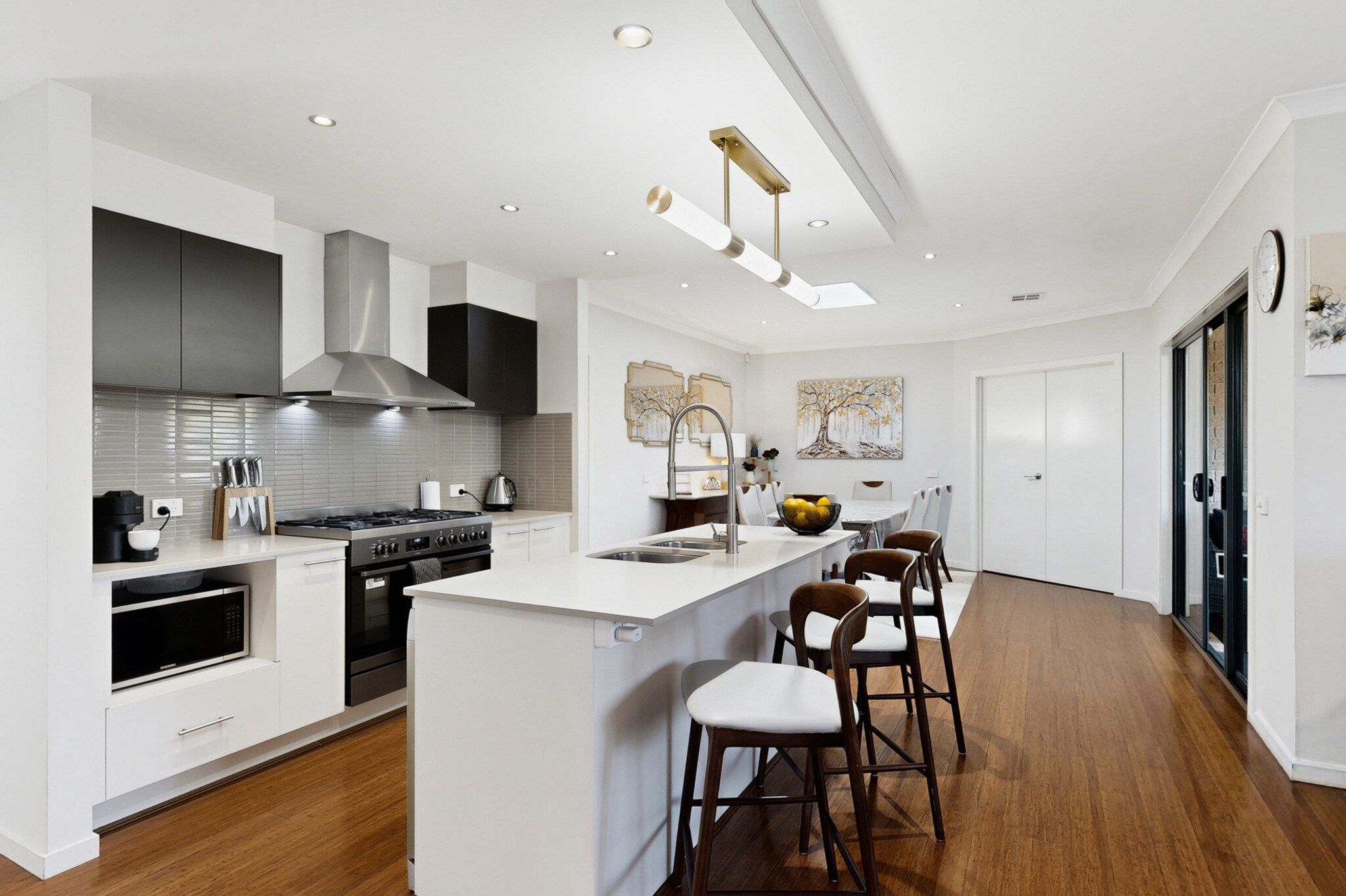 A modern kitchen with a central island, stainless steel appliances, and a dining area with bar stools.