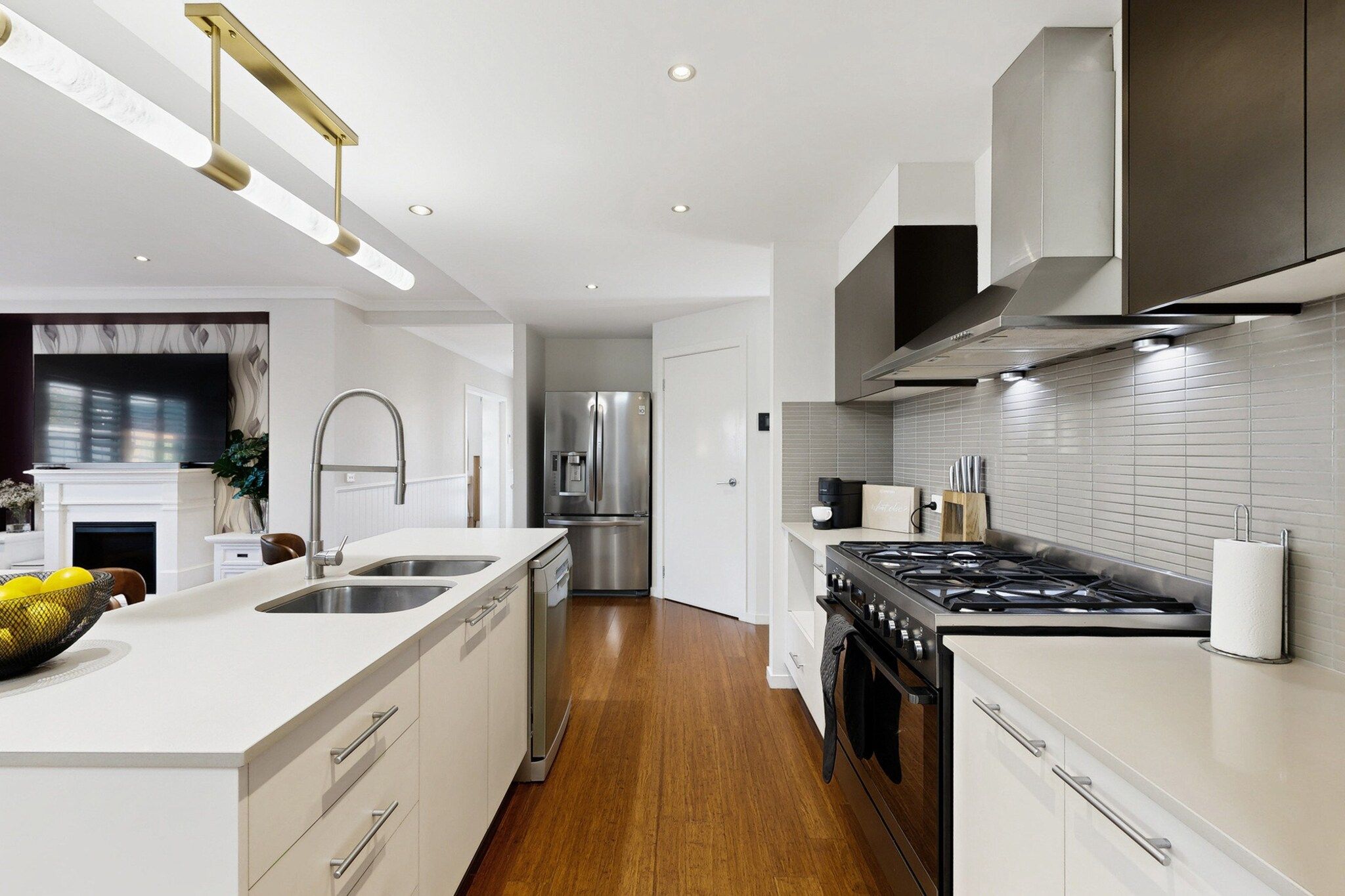 A modern kitchen with a central island, stainless steel appliances, and a wood floor.