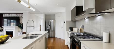 A modern kitchen with a central island, stainless steel appliances, and a wood floor.