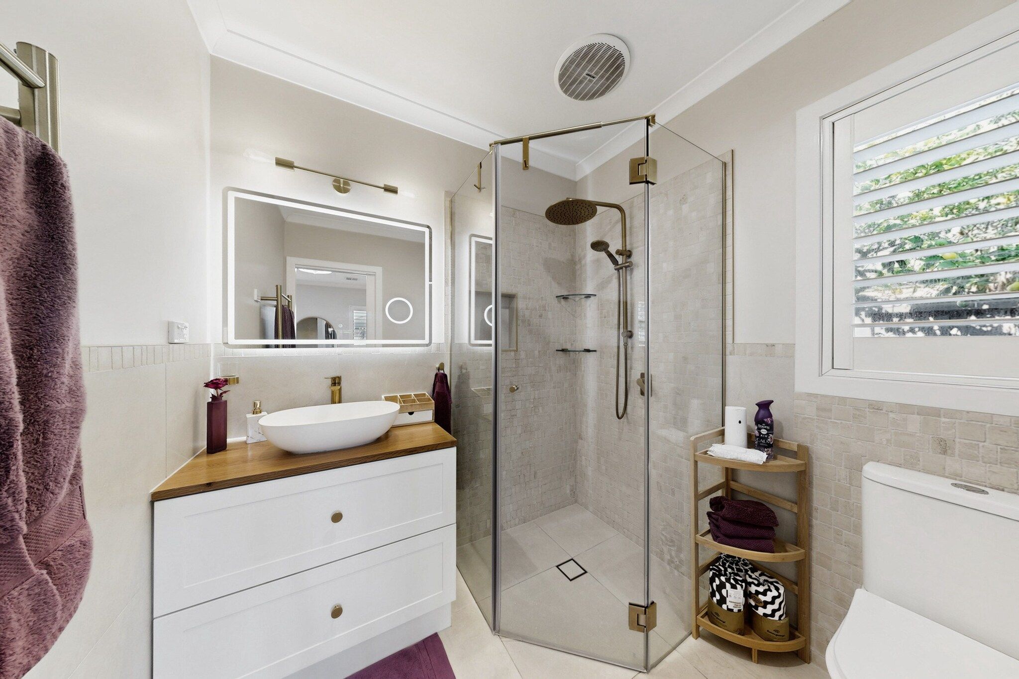 A modern bathroom with a glass-enclosed shower, a white sink, and a vanity with drawers.