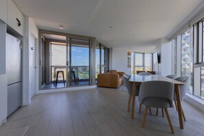 A modern kitchen with a dining area, large windows, and a view of the city. - Skyline-View 2-Bed Apartment Near Flemington (Flemington)