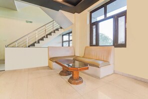 Un área de recepción con una escalera, una mesa con superficie de vidrio, un sofá de cuero y un ventanal con vistas.