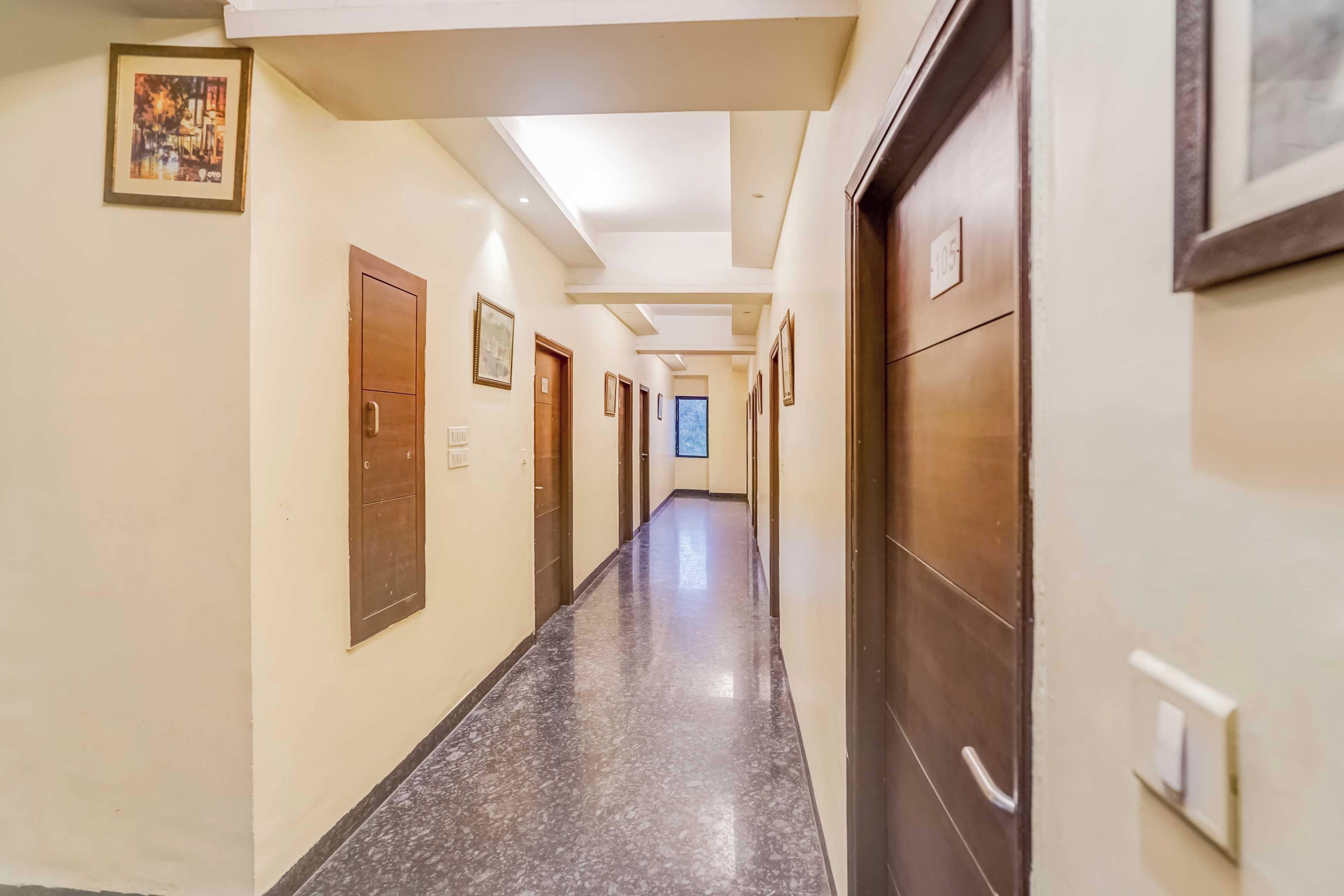 Un pasillo de hotel con varias puertas, algunas con números, y un piso de mármol.