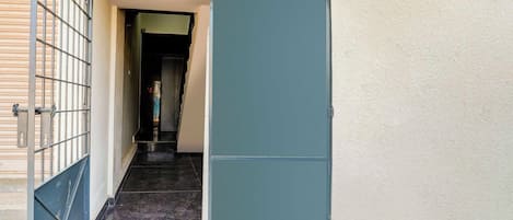 Un pasillo estrecho con una reja metálica a la izquierda y una puerta azul a la derecha.