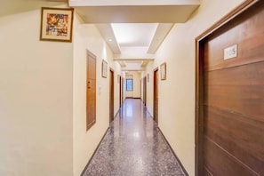 Un pasillo de hotel con puertas, un letrero con un número y un cuadro enmarcado en la pared.
